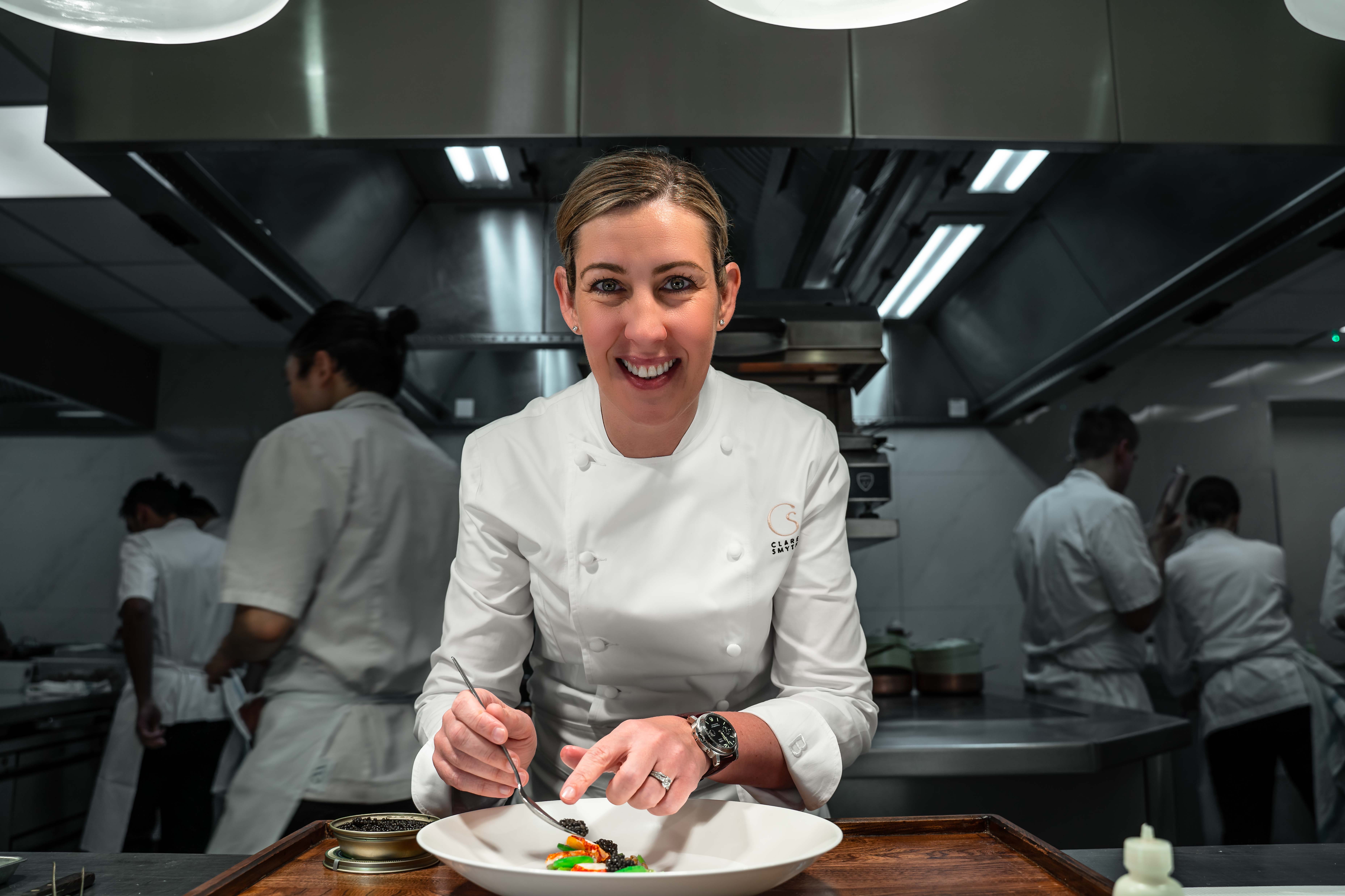 Clare Smyth plating up at a kitchen pass.