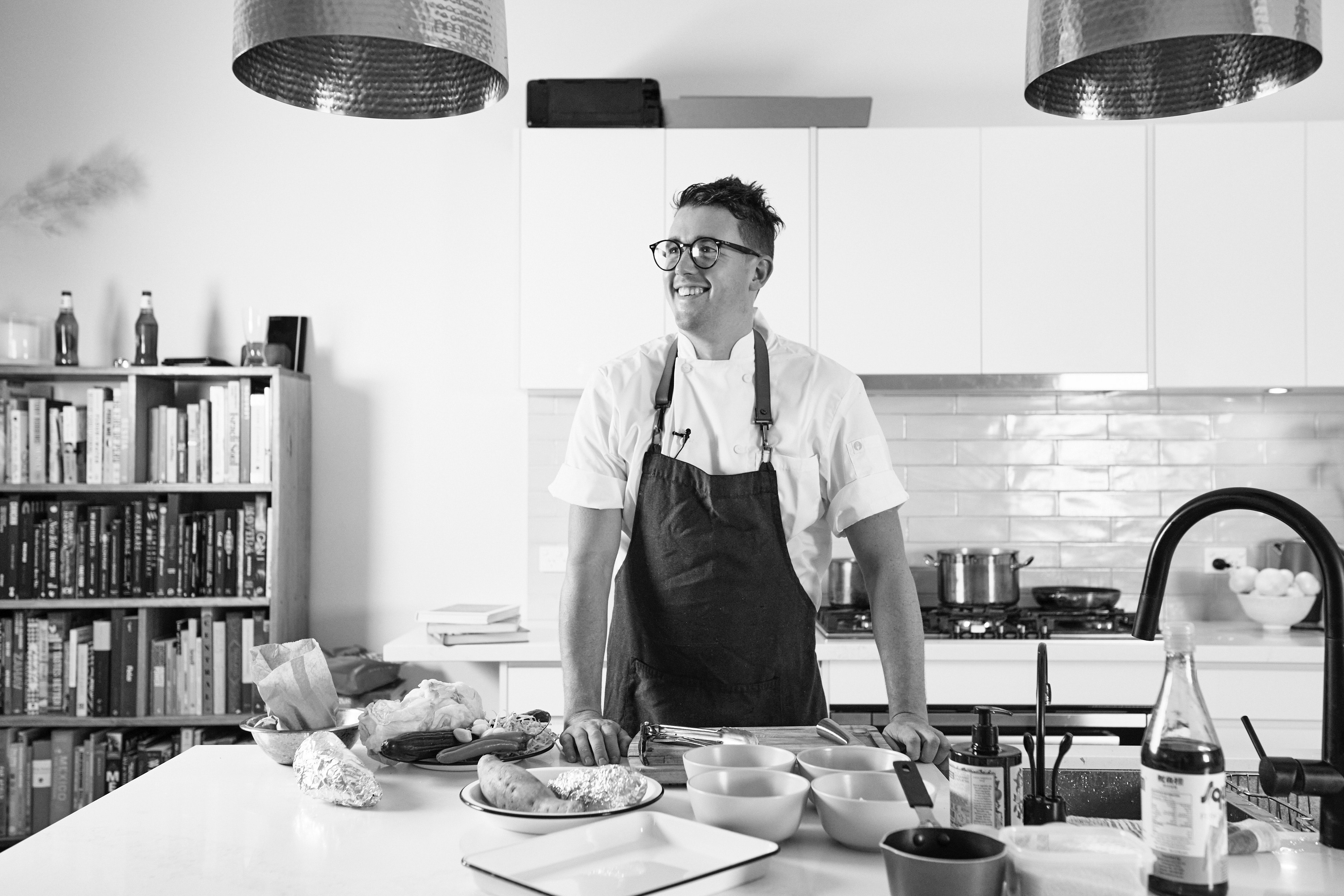 Black and white image of Chef Charlie Carrington looking away from camera and smiling in home kitchen